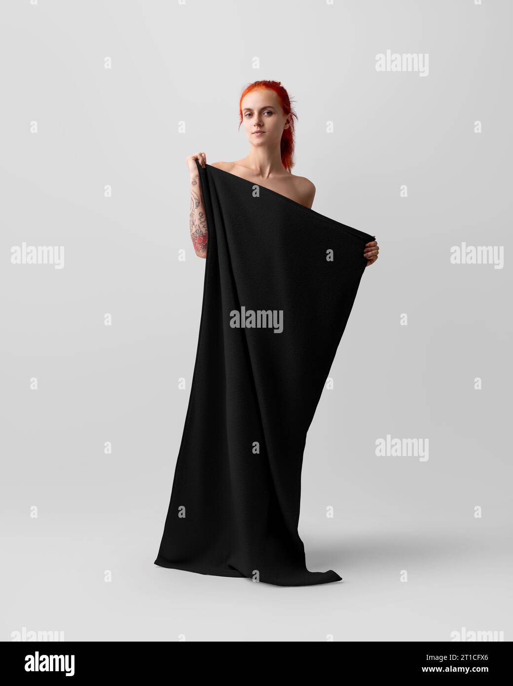 Maquette d'une serviette noire, une fille la tient en pleine hauteur pour l'image de marque, le design. Modèle de serviette isolé sur fond blanc. Photographie de produit pour Banque D'Images