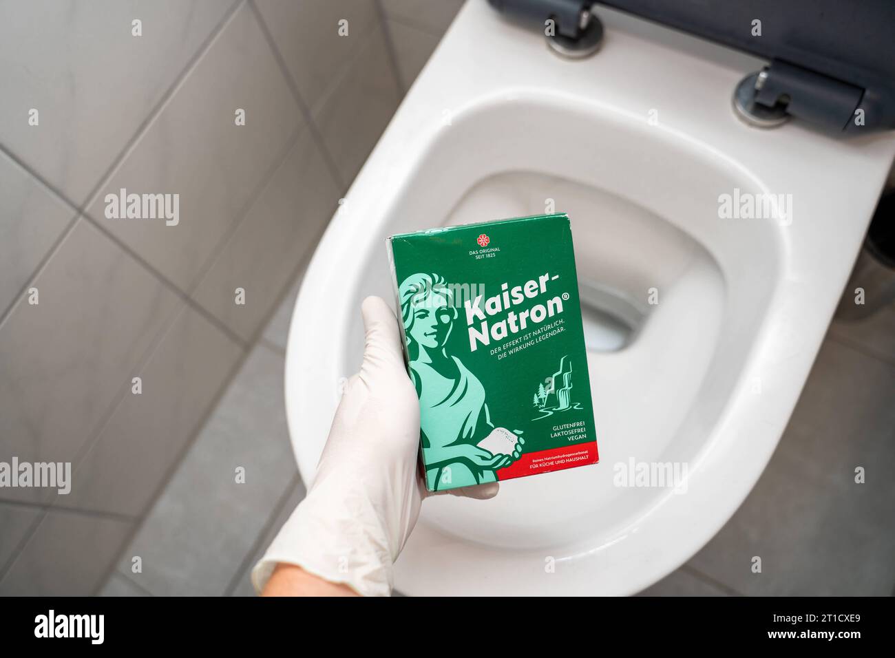 Augsbourg, Bavière, Allemagne. 29 septembre 2023. Main gantée tenant un paquet de Kaiser Natron devant une toilette. Remède maison pour le nettoyage et le débouchage *** main mit Handschuhen hält eine Packung Kaiser Natron vor eine toilette. Hausmittel zur Reinigung und zum lösen von Verstopfungen crédit : Imago/Alamy Live News Banque D'Images