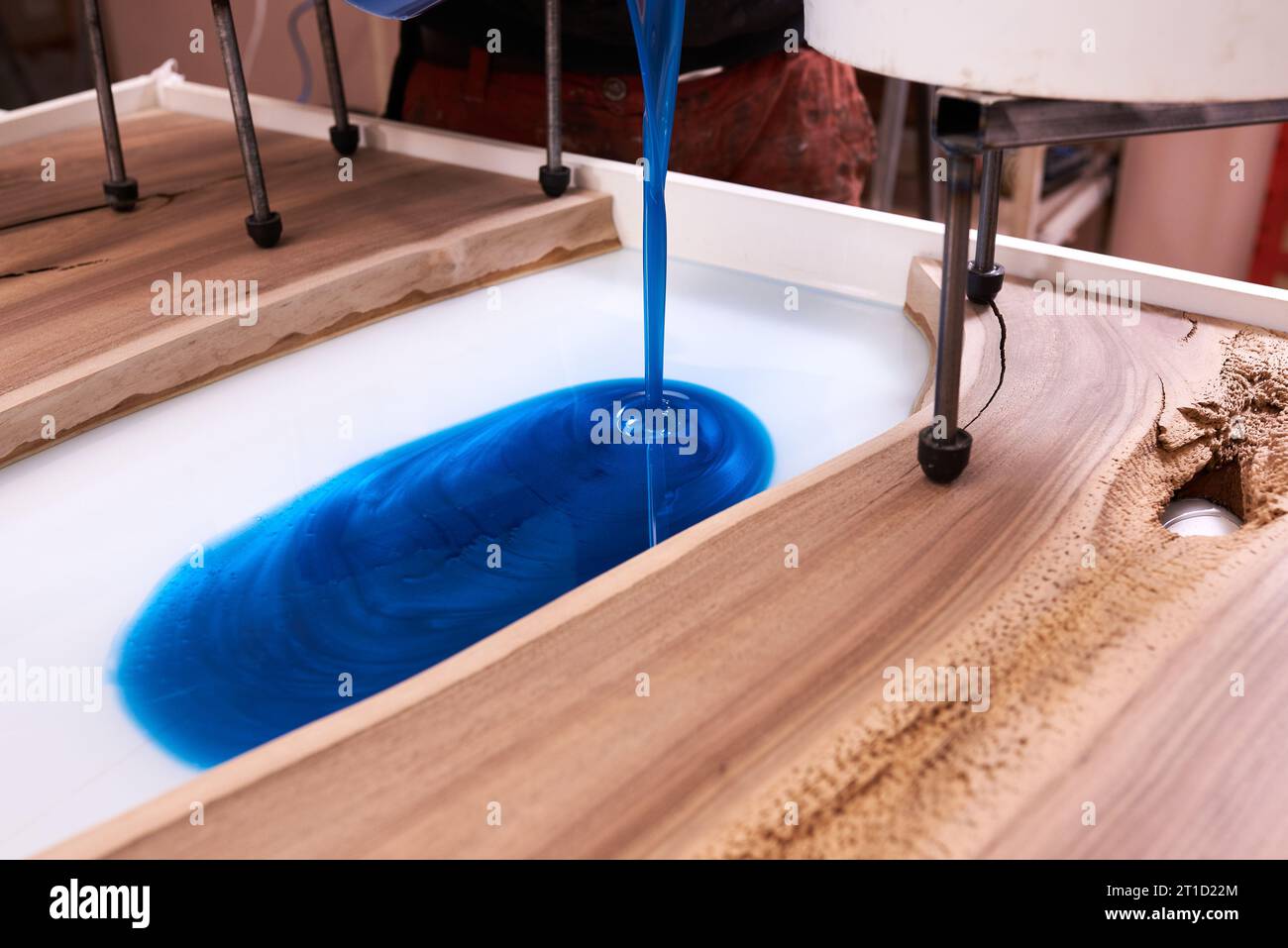 Procédé de fabrication d'une table en résine artisanale et en bois. L'époxy liquide est versé dans un moule avec des ébauches en bois. gros plan Banque D'Images