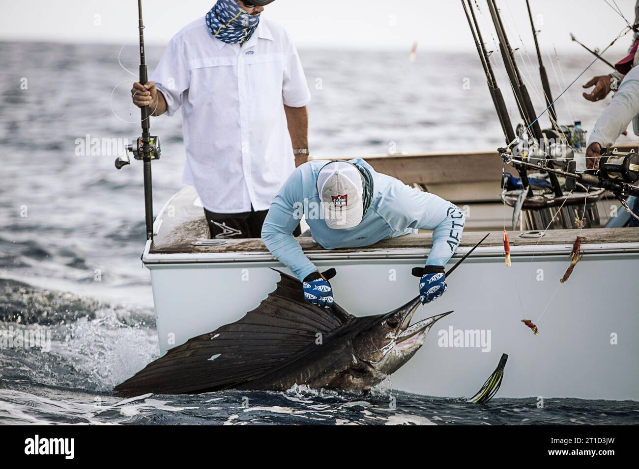 Un pêcheur tient un voilier à côté du bateau. Banque D'Images