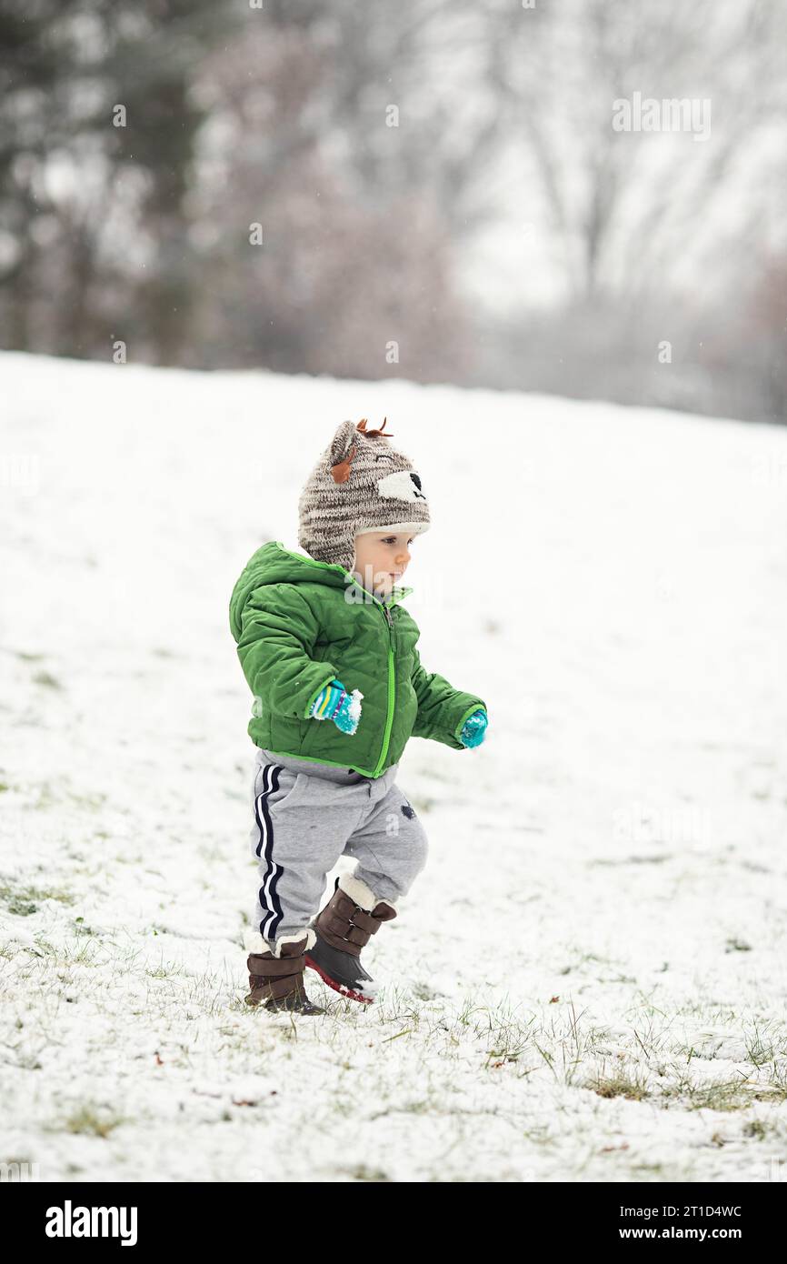 Tout-petit marchant dans la neige portant des vêtements d'hiver Banque D'Images
