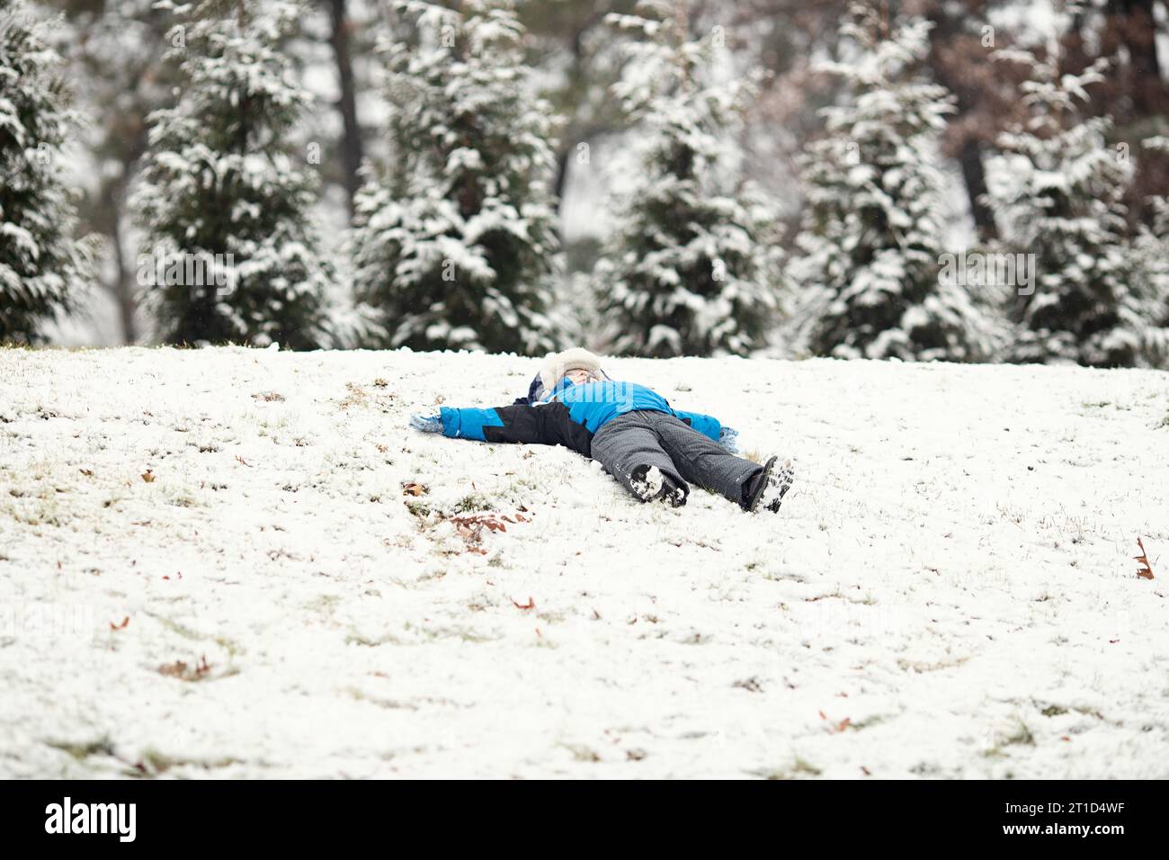 Enfant faisant des anges de neige dans la neige fraîche tombée Banque D'Images