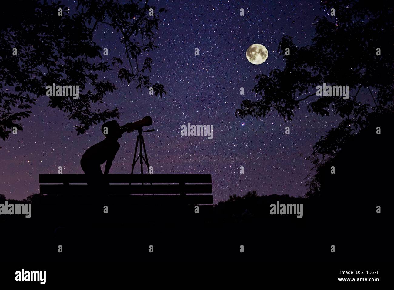 Garçon la nuit, regardant les étoiles et la pleine lune à travers un télescope. Banque D'Images