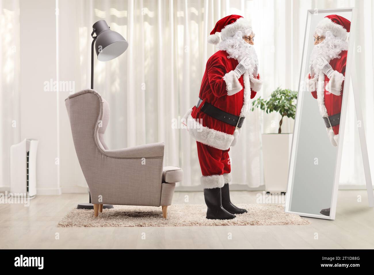 Plan de profil en longueur du père noël se préparant devant un miroir à la maison Banque D'Images