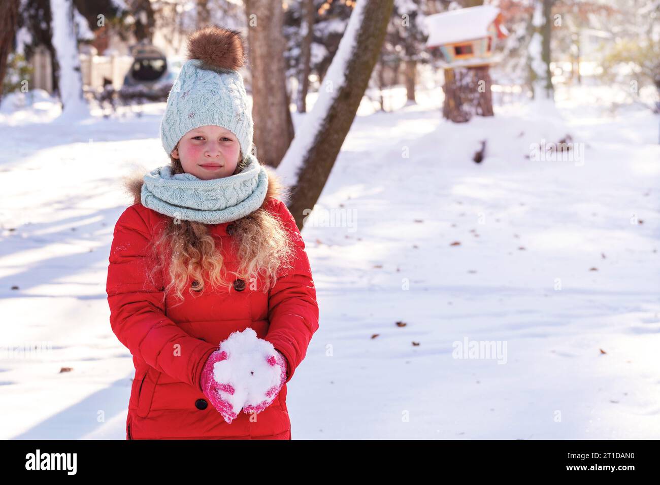 La belle fille joyeuse dans la forêt enneigée. Portrait de l'enfant heureux en hiver. Paysage hivernal, scène. Neige dans les mains d'un chi Banque D'Images