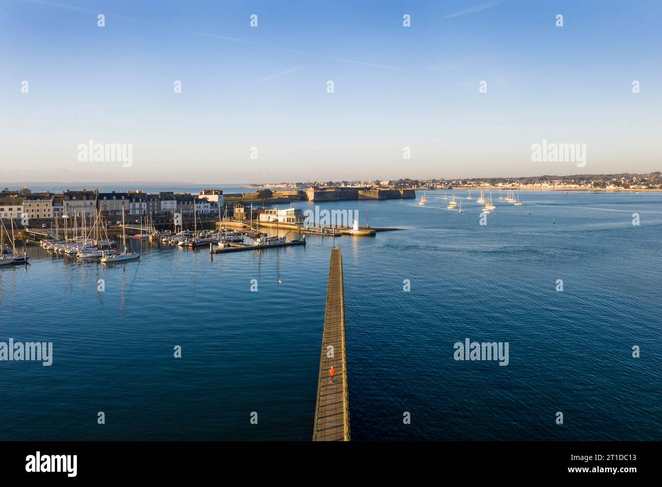 Port-Louis (Bretagne, nord-ouest de la France) : vue aérienne de l'embarcadère de la pointe de Kerzo et de la ville de Port-Louis en arrière-plan. Homme marchant a Banque D'Images