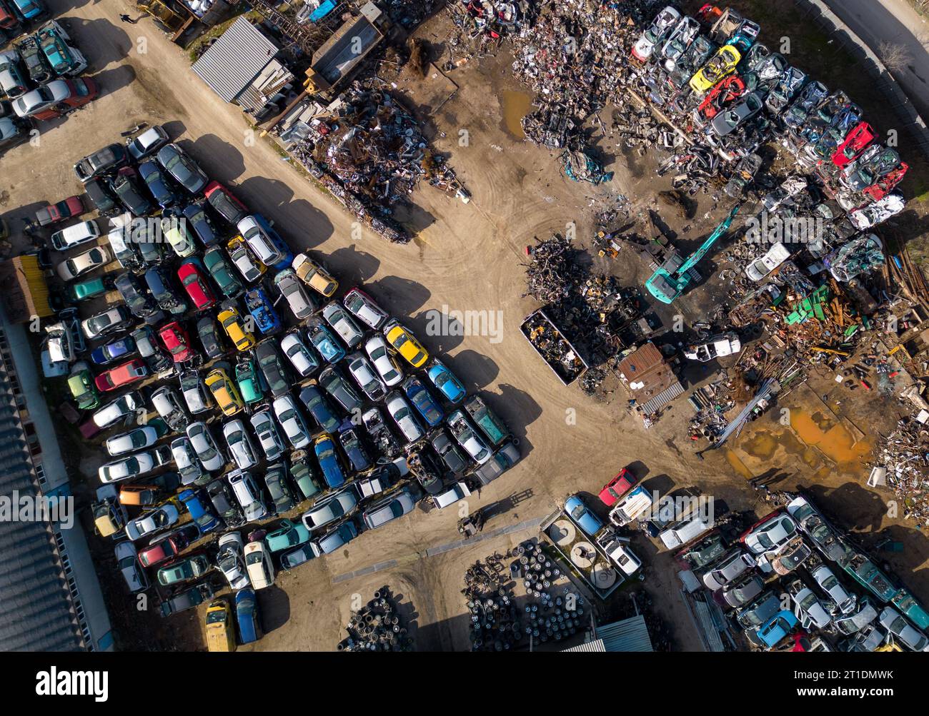 vue aérienne d'une décharge de voiture, où une machine est vue séparant les vieilles voitures en ferraille. La collection massive de voitures abandonnées et la machinerie lourde nous Banque D'Images