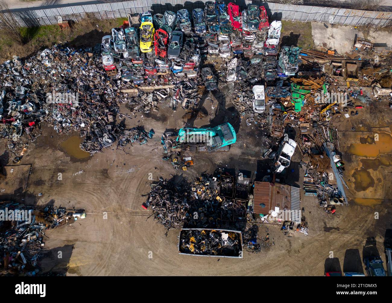 vue aérienne d'une décharge de voiture, où une machine est vue séparant les vieilles voitures en ferraille. La collection massive de voitures abandonnées et la machinerie lourde nous Banque D'Images