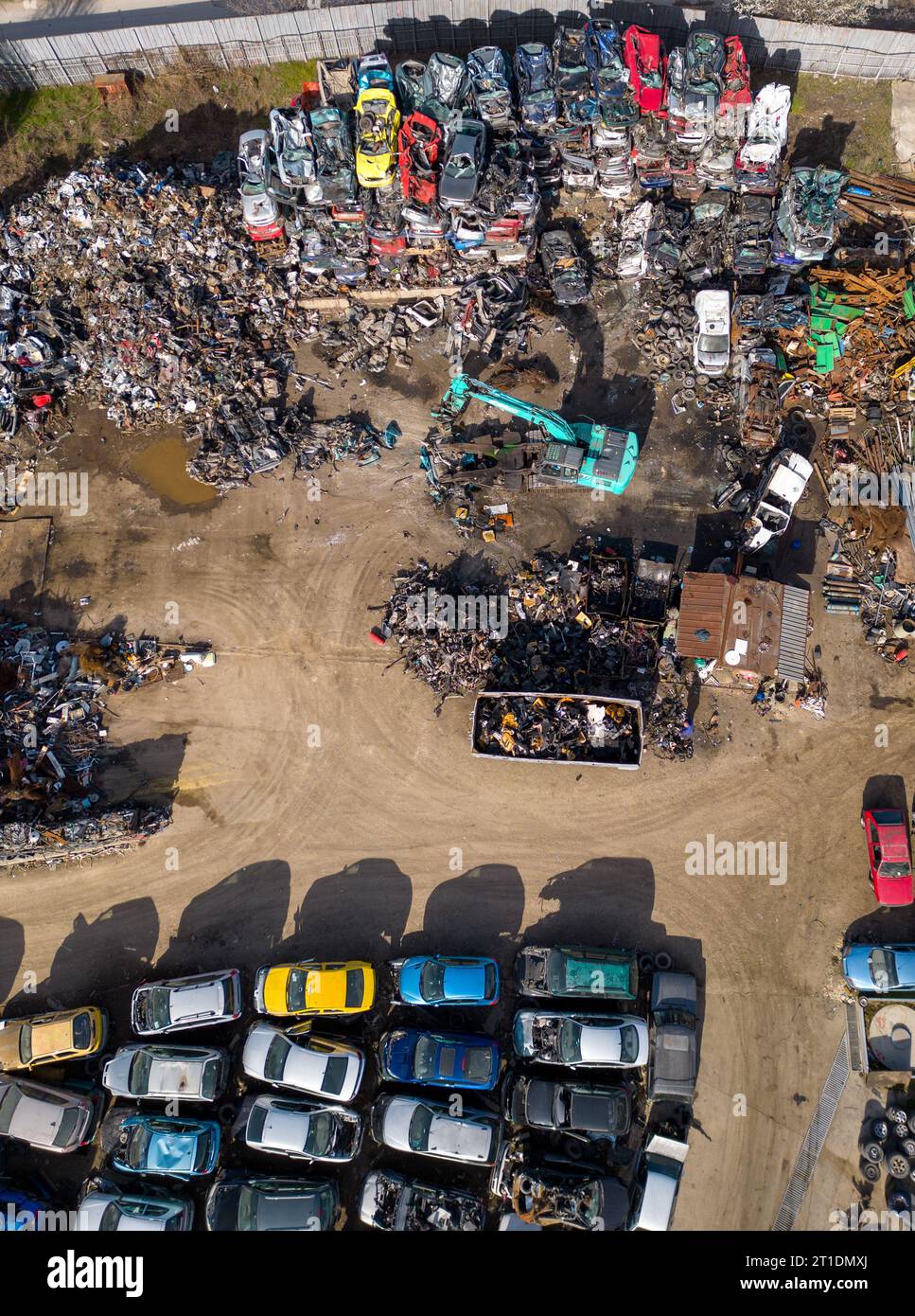vue aérienne d'une décharge de voiture, où une machine est vue séparant les vieilles voitures en ferraille. La collection massive de voitures abandonnées et la machinerie lourde nous Banque D'Images