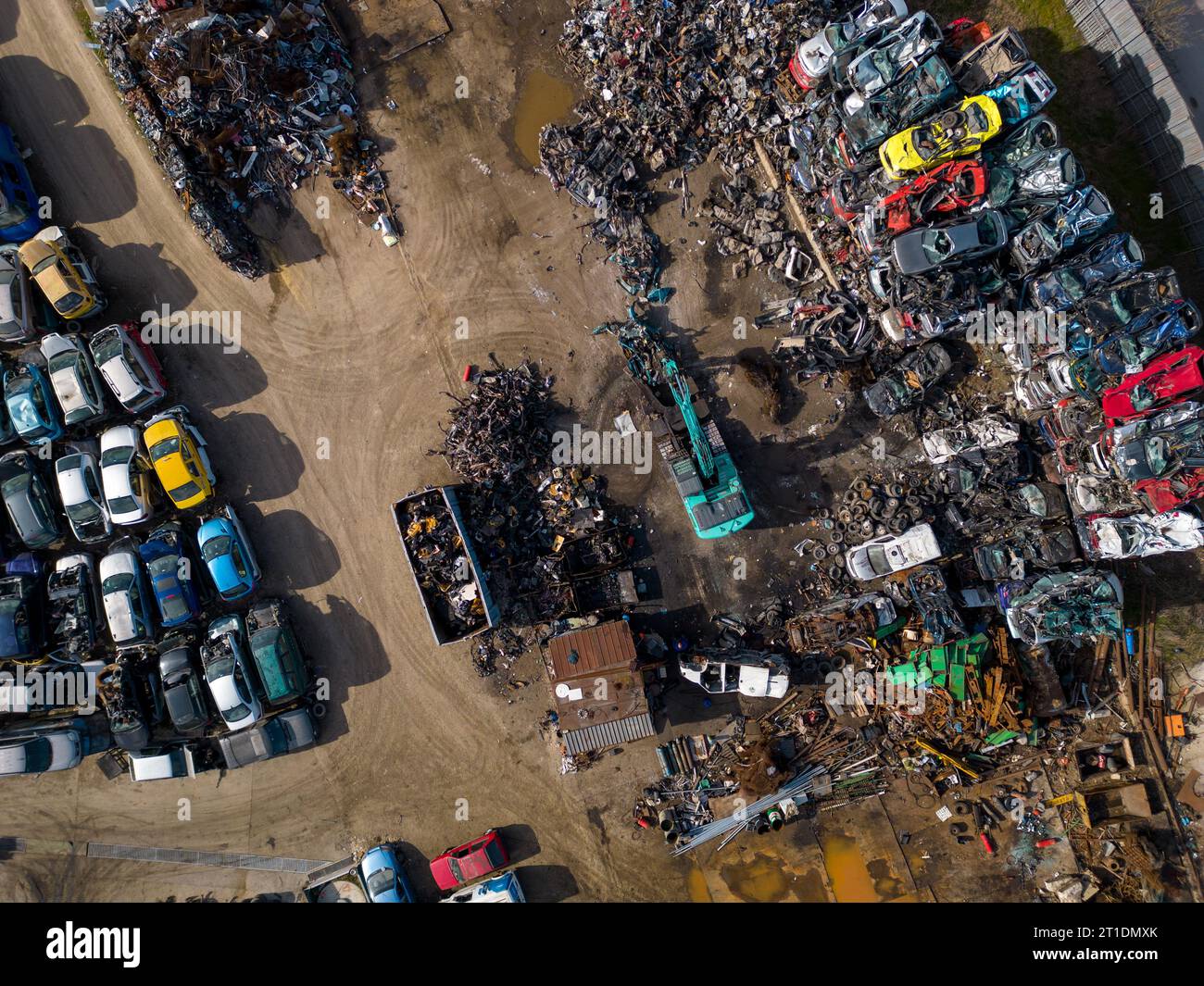 vue aérienne d'une décharge de voiture, où une machine est vue séparant les vieilles voitures en ferraille. La collection massive de voitures abandonnées et la machinerie lourde nous Banque D'Images