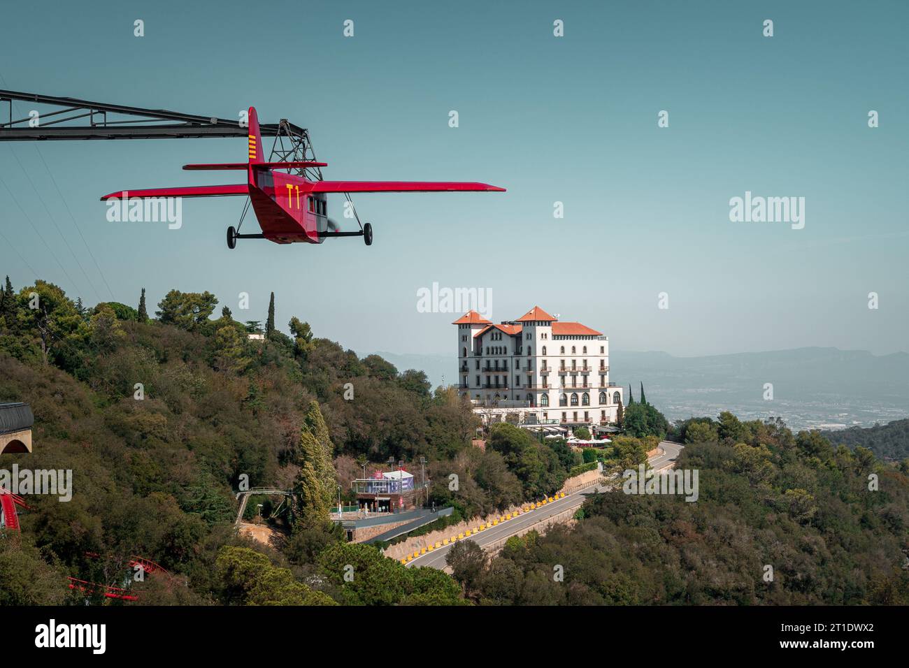 Carrousel sous la forme d'un avion volant rouge au parc d'attractions Tibidabo à Barcelone. Gran Hotel la Florida en arrière-plan Banque D'Images