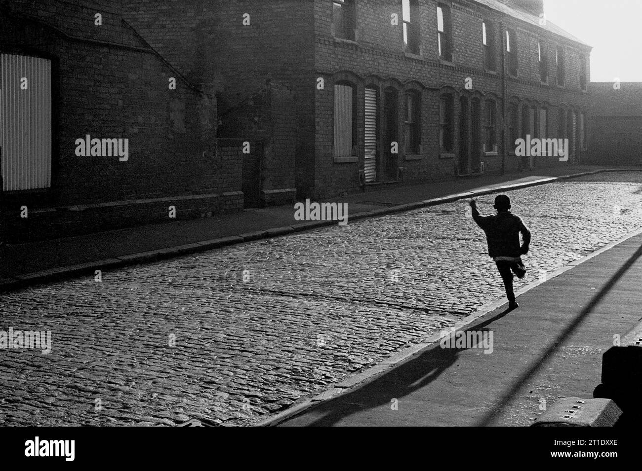 Garçon courant le long d'une rue pavée Sanderson pendant le nettoyage des bidonvilles et la démolition de Victorian St ann's, Nottingham. 1969-1972 Banque D'Images