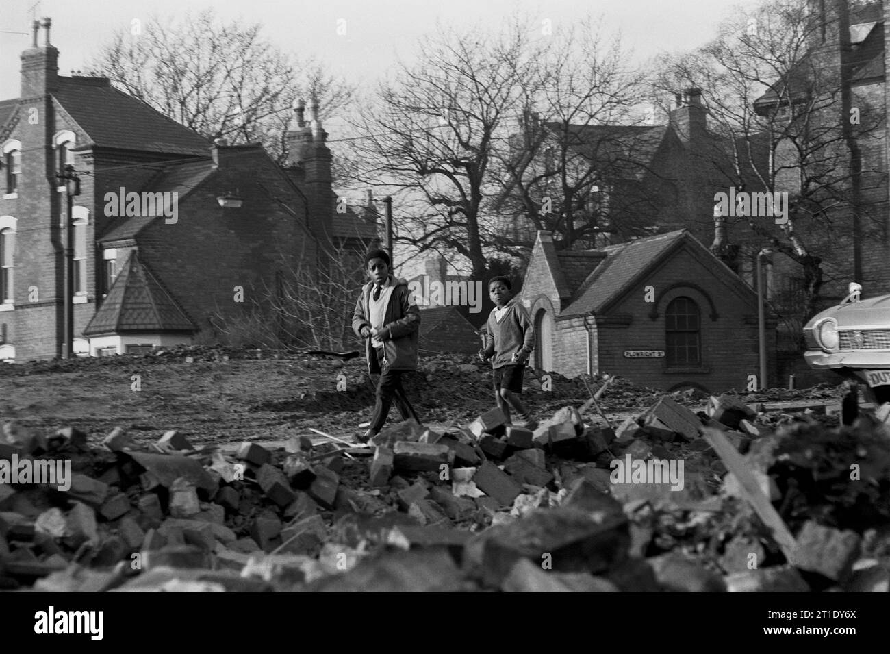 Deux écoliers mangeant des bonbons tout en rentrant chez eux à travers les décombres de démolition pendant le nettoyage des bidonvilles de St ann's, Nottingham. 1969-1972 Banque D'Images