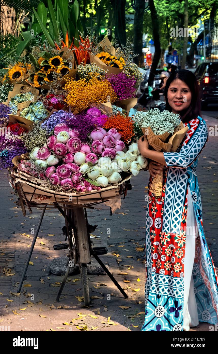 Femme à ao dai avec des fleurs sur Phan Dinh Phung Street, Hanoi, Vietnam Banque D'Images