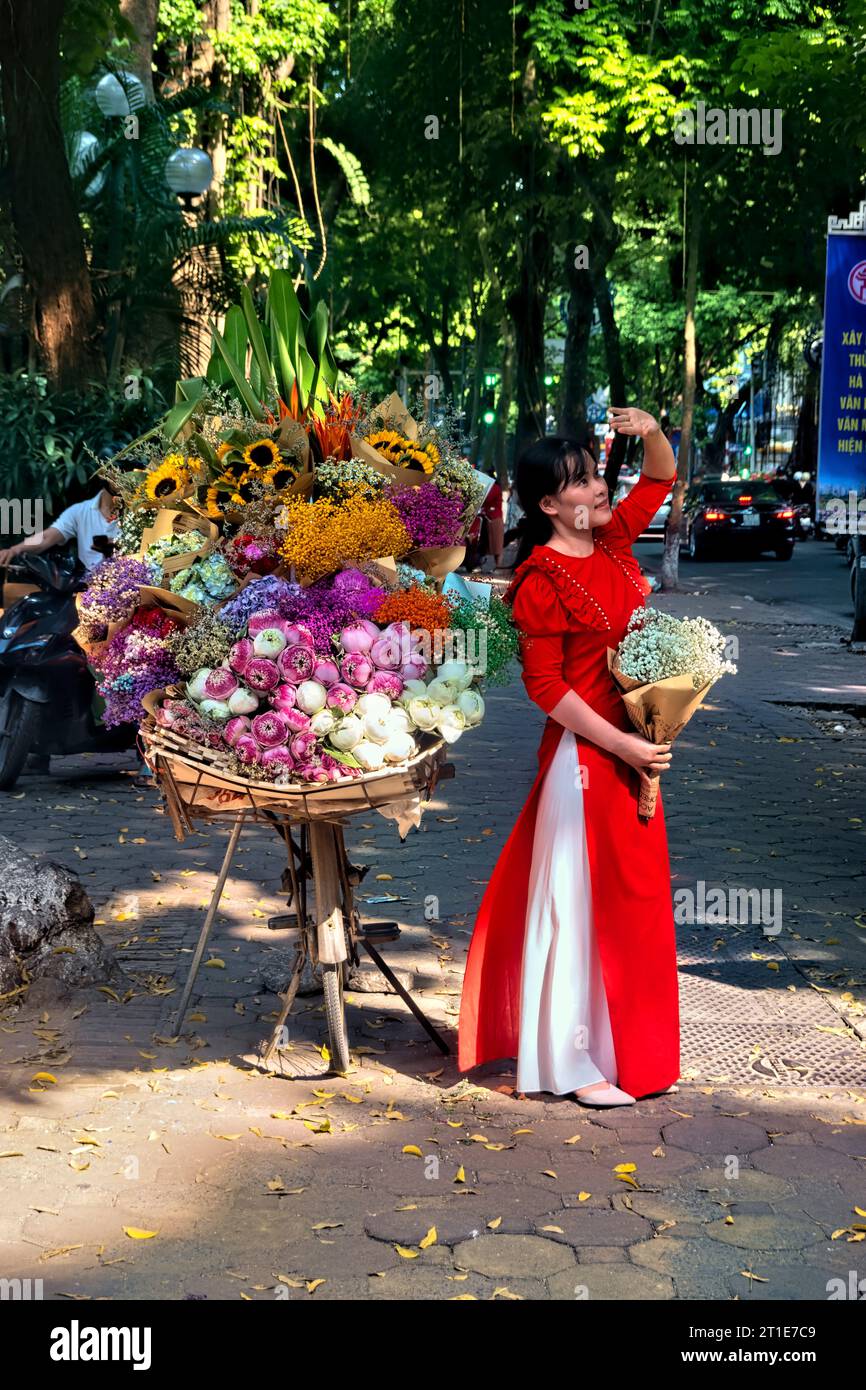 Femme à ao dai avec des fleurs sur Phan Dinh Phung Street, Hanoi, Vietnam Banque D'Images