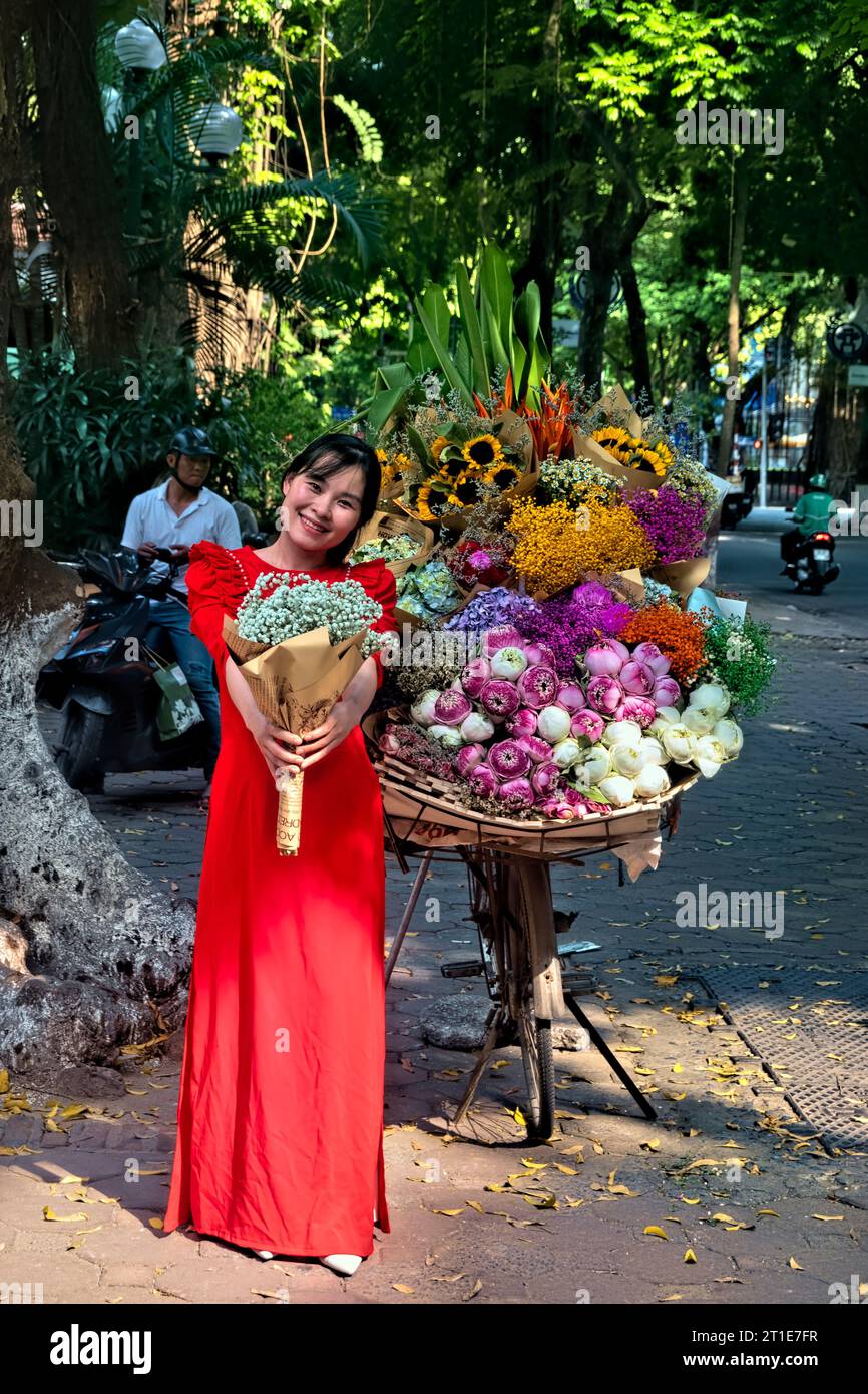 Femme à ao dai avec des fleurs sur Phan Dinh Phung Street, Hanoi, Vietnam Banque D'Images