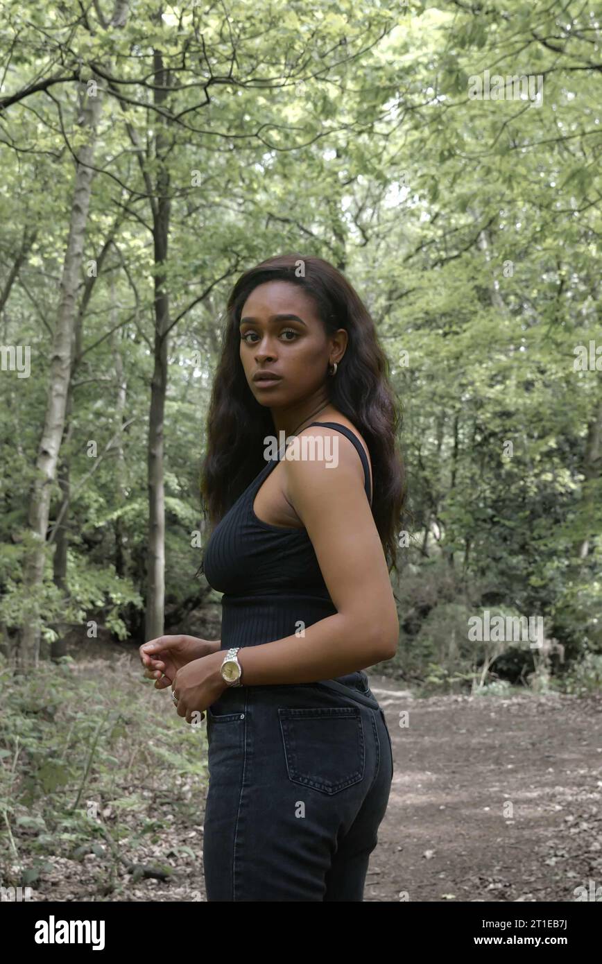 jeune femme noire portant un débardeur noir et un jean dans les bois Banque D'Images