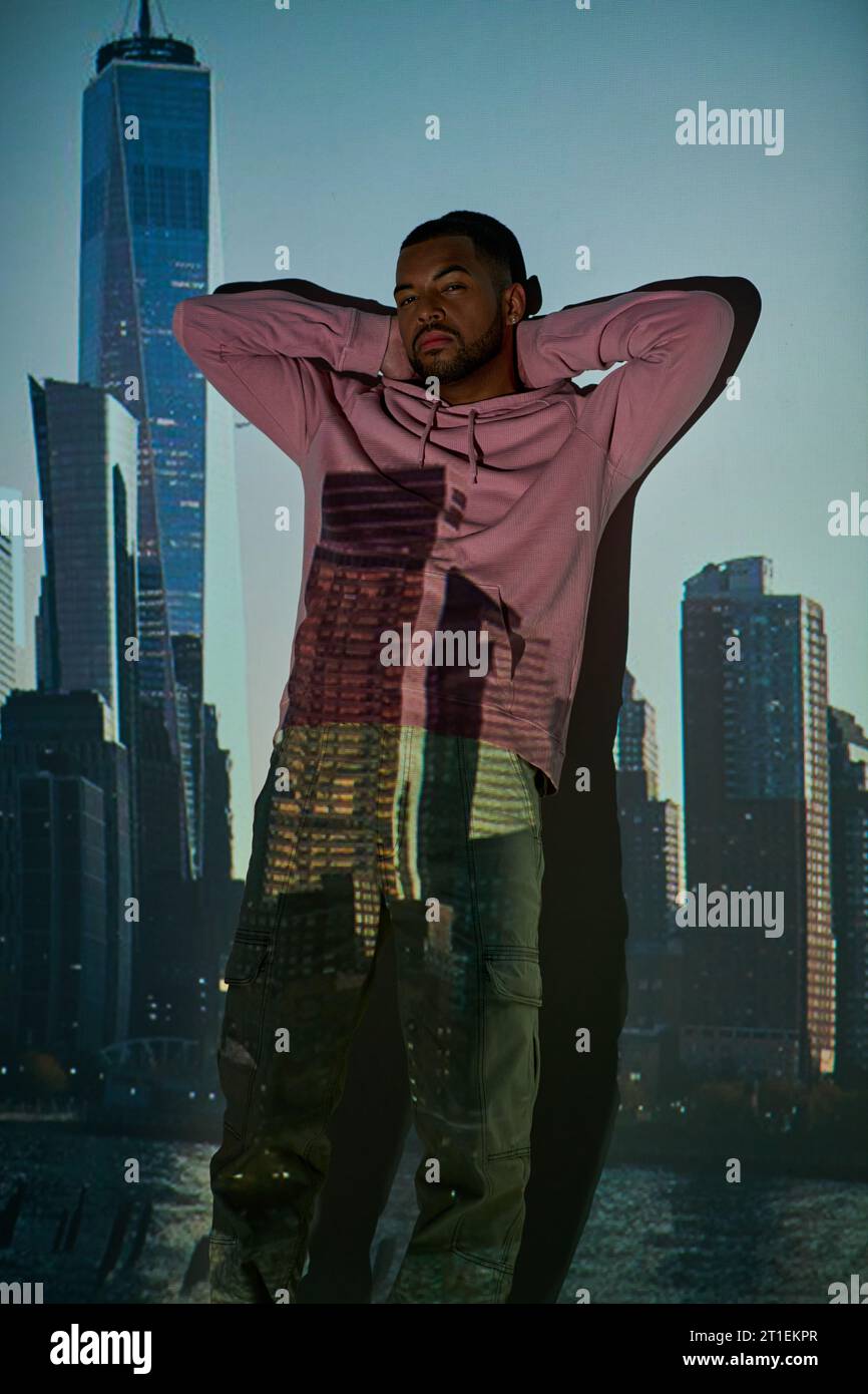 bel homme afro-américain debout par le mur avec les mains croisées derrière la tête, concept de mode Banque D'Images