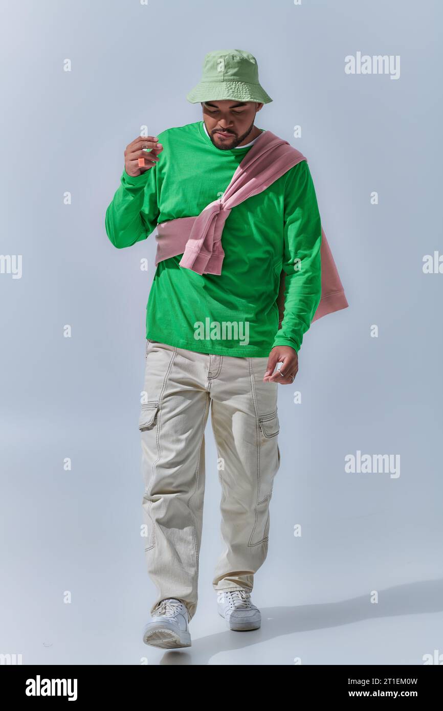 jeune mannequin homme barbu en sweat-shirt vert posant en mouvement regardant vers le bas, concept de mode Banque D'Images