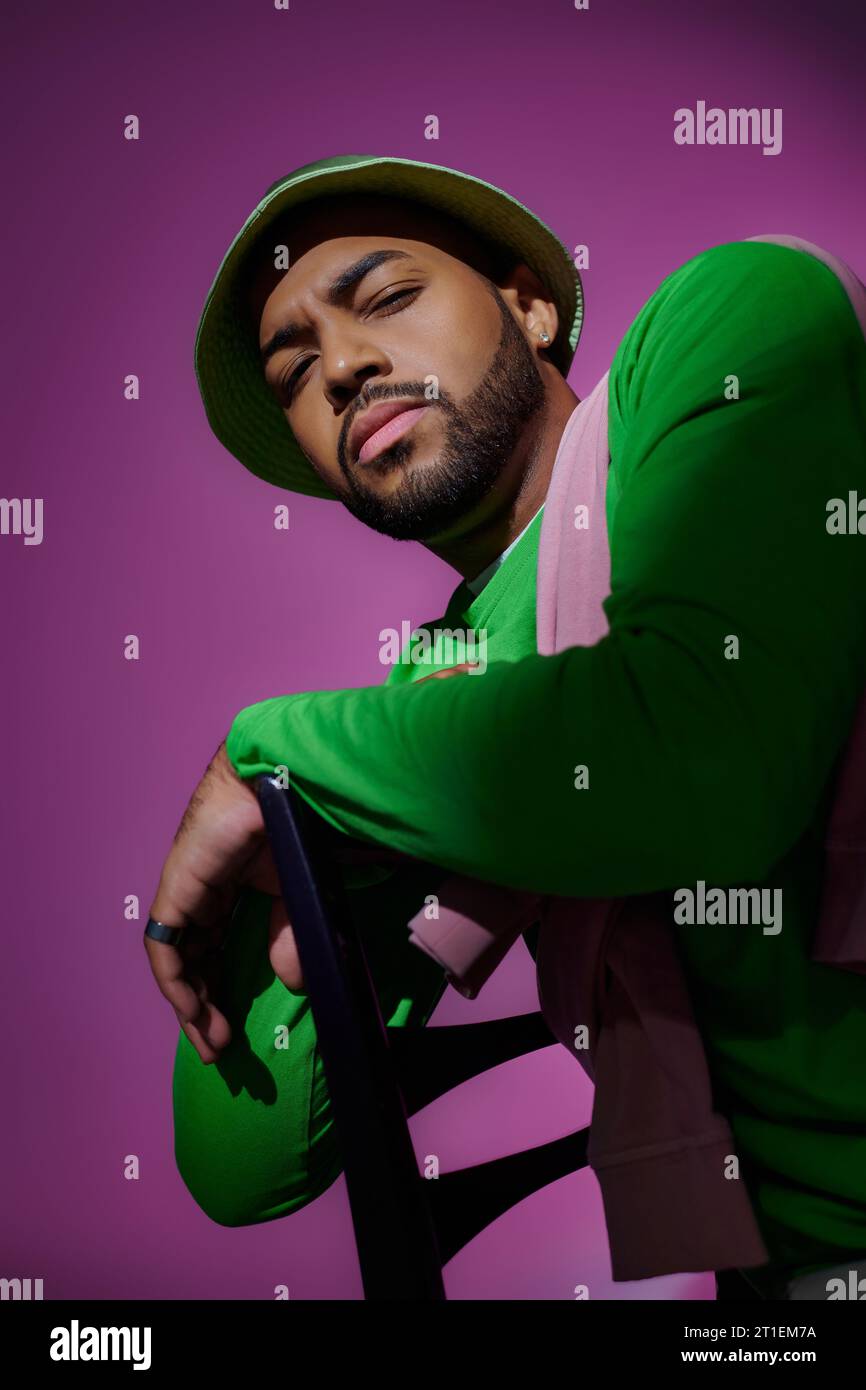 jeune modèle masculin sérieux dans une tenue tendance décontractée regardant suspicieusement à la caméra, concept de mode Banque D'Images