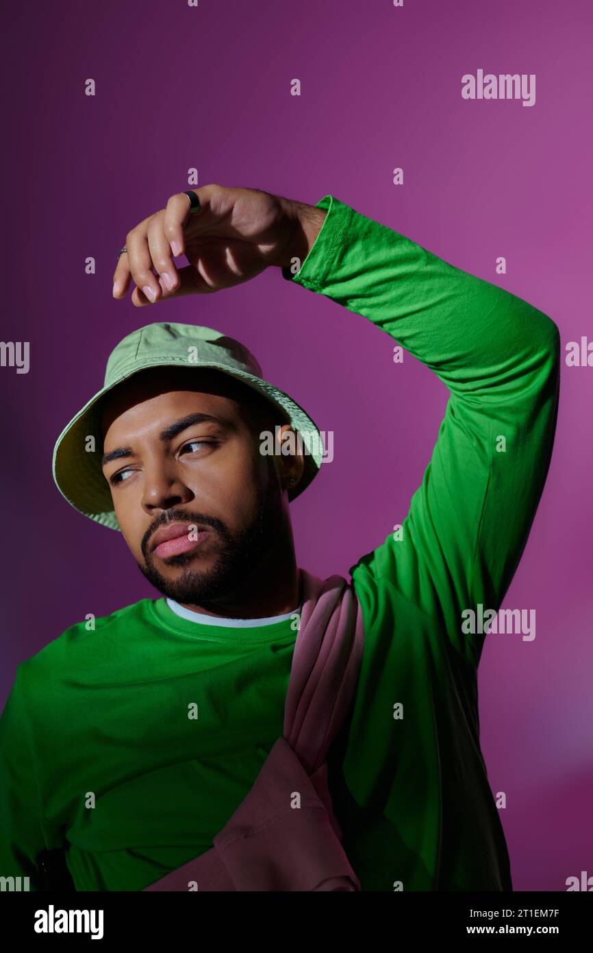 jeune mannequin homme barbu en tenue décontractée élégante posant sur fond violet, concept de mode Banque D'Images