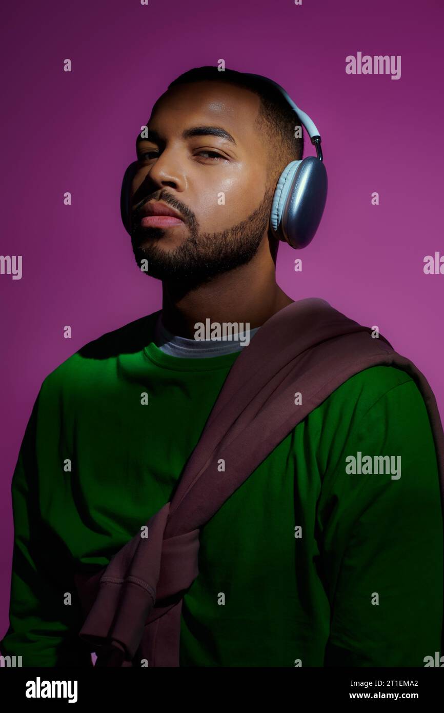 bon modèle masculin afro-américain à la recherche en sweat-shirt vert avec écouteurs, concept de mode Banque D'Images