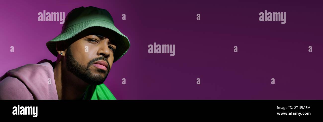 modèle masculin élégant en panama vert tendance regardant suspicieusement à la caméra, concept de mode, bannière Banque D'Images