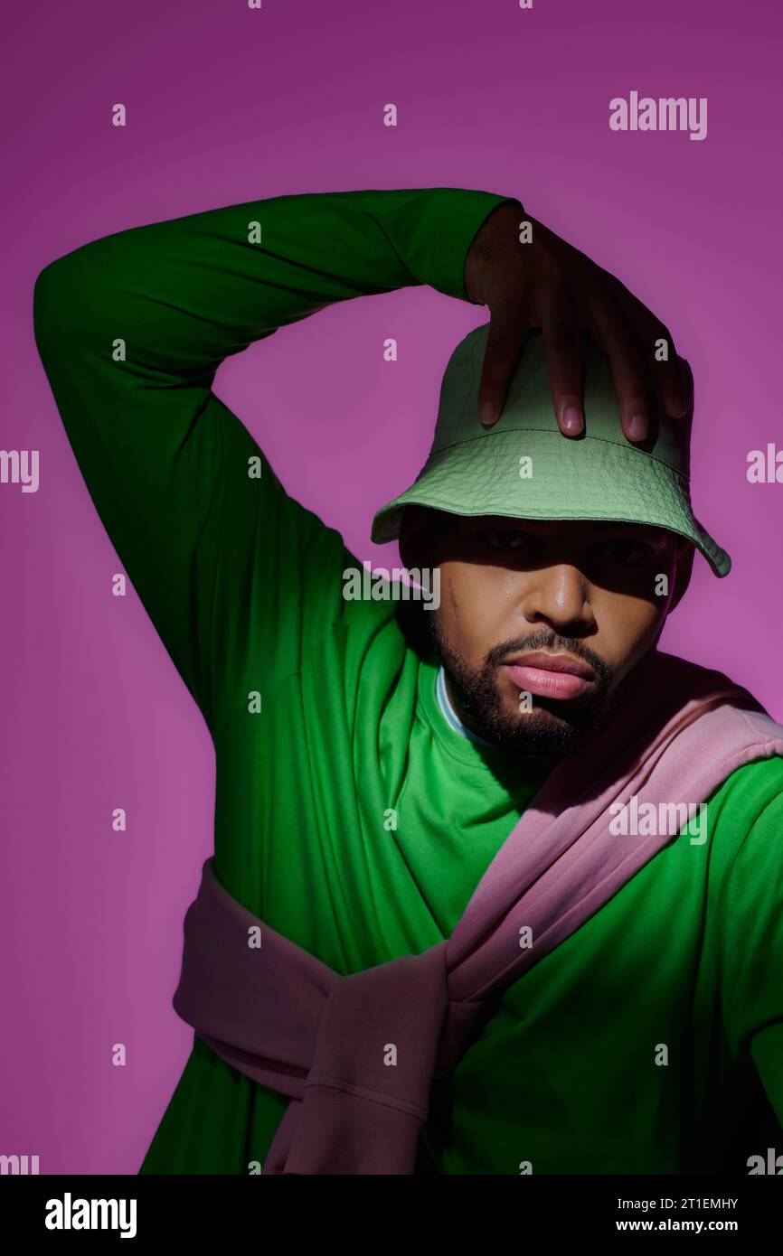 beau modèle masculin afro-américain posant avec sa main sur le panama vert, concept de mode Banque D'Images