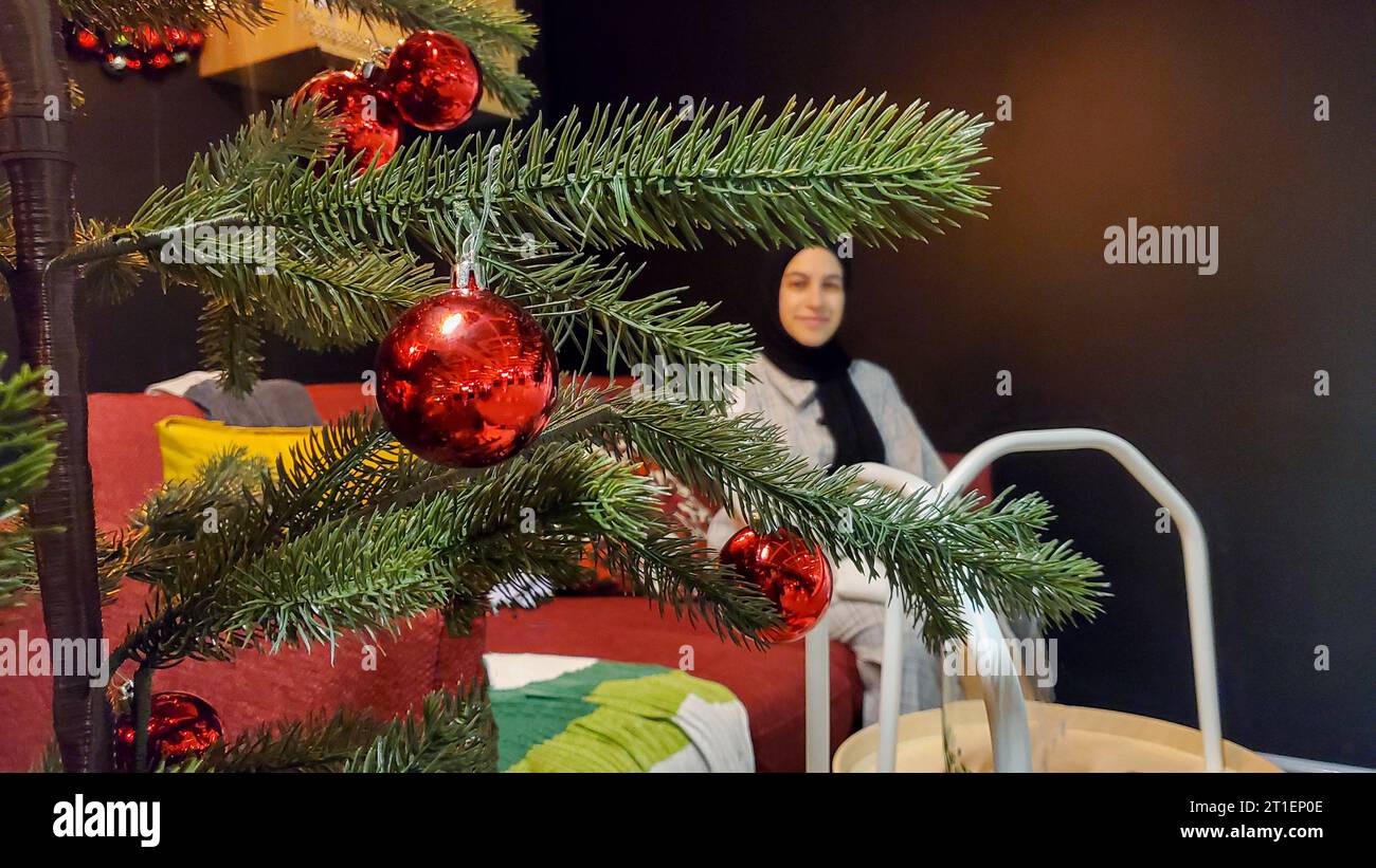 Sapin de Noël avec décorations rouges dans le salon avec canapé confortable et coussins Banque D'Images