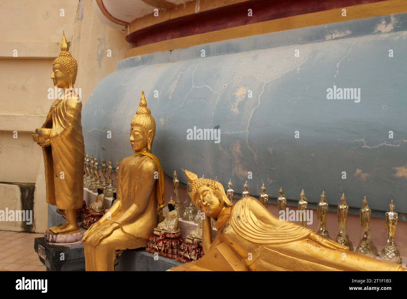 Deux statues dorées de Bouddha debout côte à côte dans une pièce aux murs bleus, créant une atmosphère paisible Banque D'Images