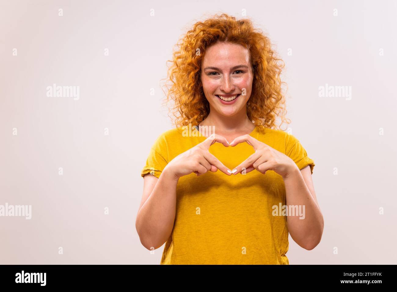 Image de belle femme de gingembre montrant la forme de coeur avec les mains. Banque D'Images