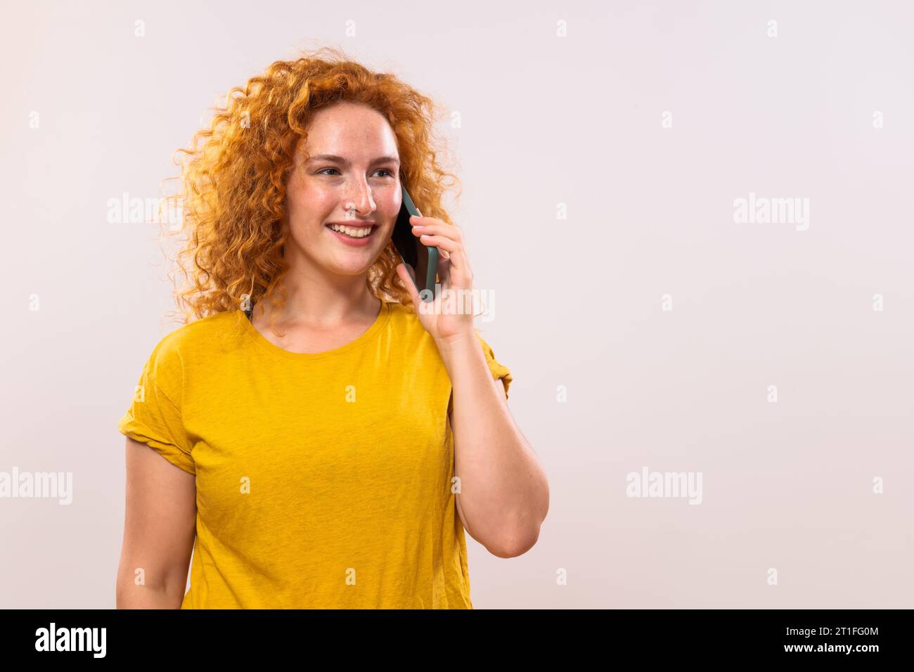 Image d'une femme gingembre heureuse parlant au téléphone. Banque D'Images
