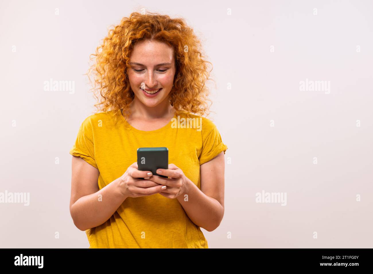 Image de femme heureuse de gingembre utilisant le téléphone. Banque D'Images