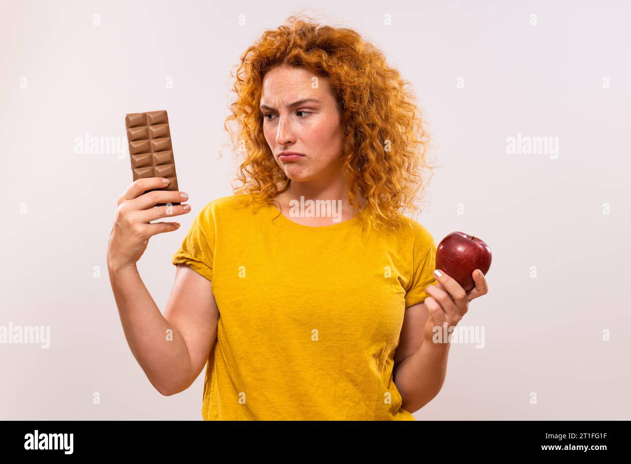 Femme de gingembre est triste parce qu'elle doit manger des fruits, elle préfère manger du chocolat. Banque D'Images