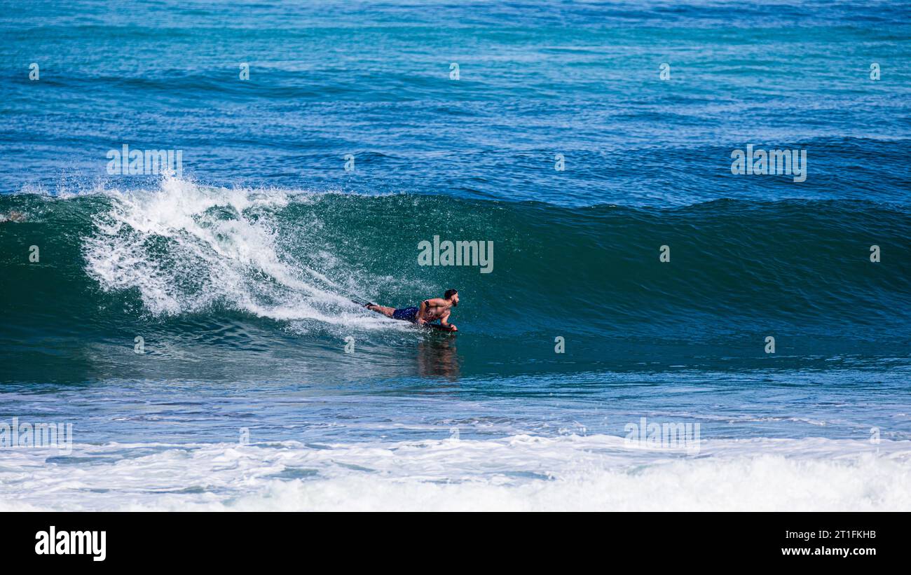 Homme allongé sur son surf dans une vague à Anglet, France Banque D'Images