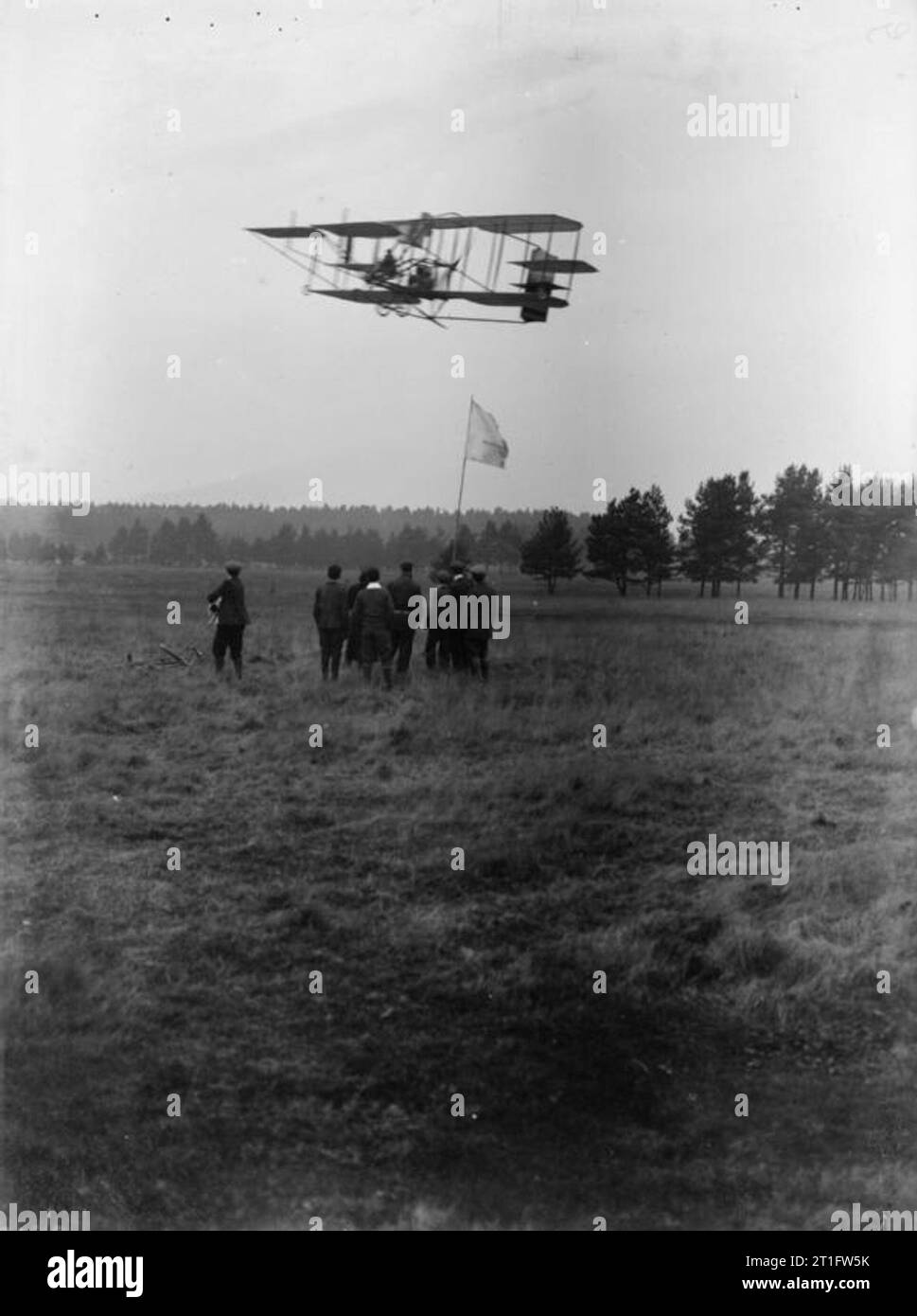 L'aviation en Grande-Bretagne avant la Première Guerre mondiale avion Cody Mark II en vol pendant le procès du Trophée Michelin avec un groupe de spectateurs avec chien et location s ci-dessous par un drapeau. L'aéronef est floue en raison de son mouvement. Cody construit cet avion en 1910 ; l'avion avait été dans plusieurs plantages et souffre généralement de l'utilisation constante. La conception de cet appareil suivie des lignes similaires à la précédente si l'envergure est plus courte d'environ six pieds et la surface alaire autour d'une troisième plus petite. La seule hélice était initialement destiné à être alimenté par deux HP 60 gr Banque D'Images