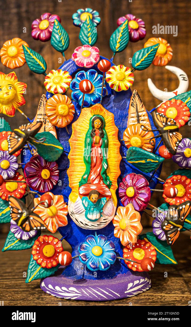 Sculpture en argile de la Vierge de Guadalupe entourée de fleurs de Michoacan, Mexique. Banque D'Images