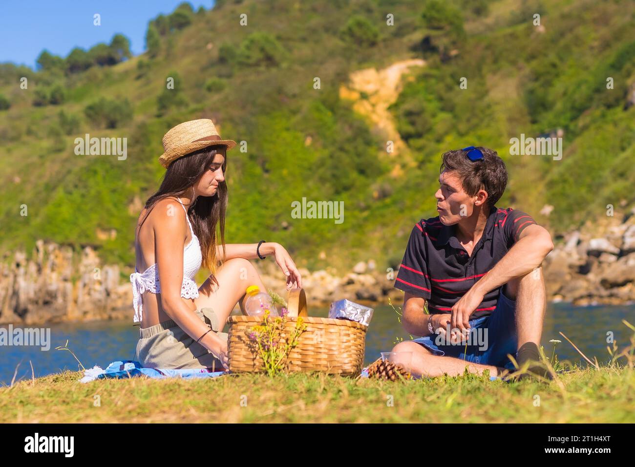 Un jeune couple caucasien sur le pique-nique dans les montagnes au bord de la mer en profitant de la chaleur, style de vie d'été Banque D'Images