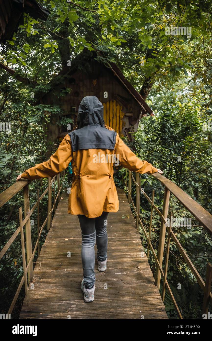Une jeune femme en veste jaune visitant une maison hantée dans une forêt. Photographie mystique Banque D'Images