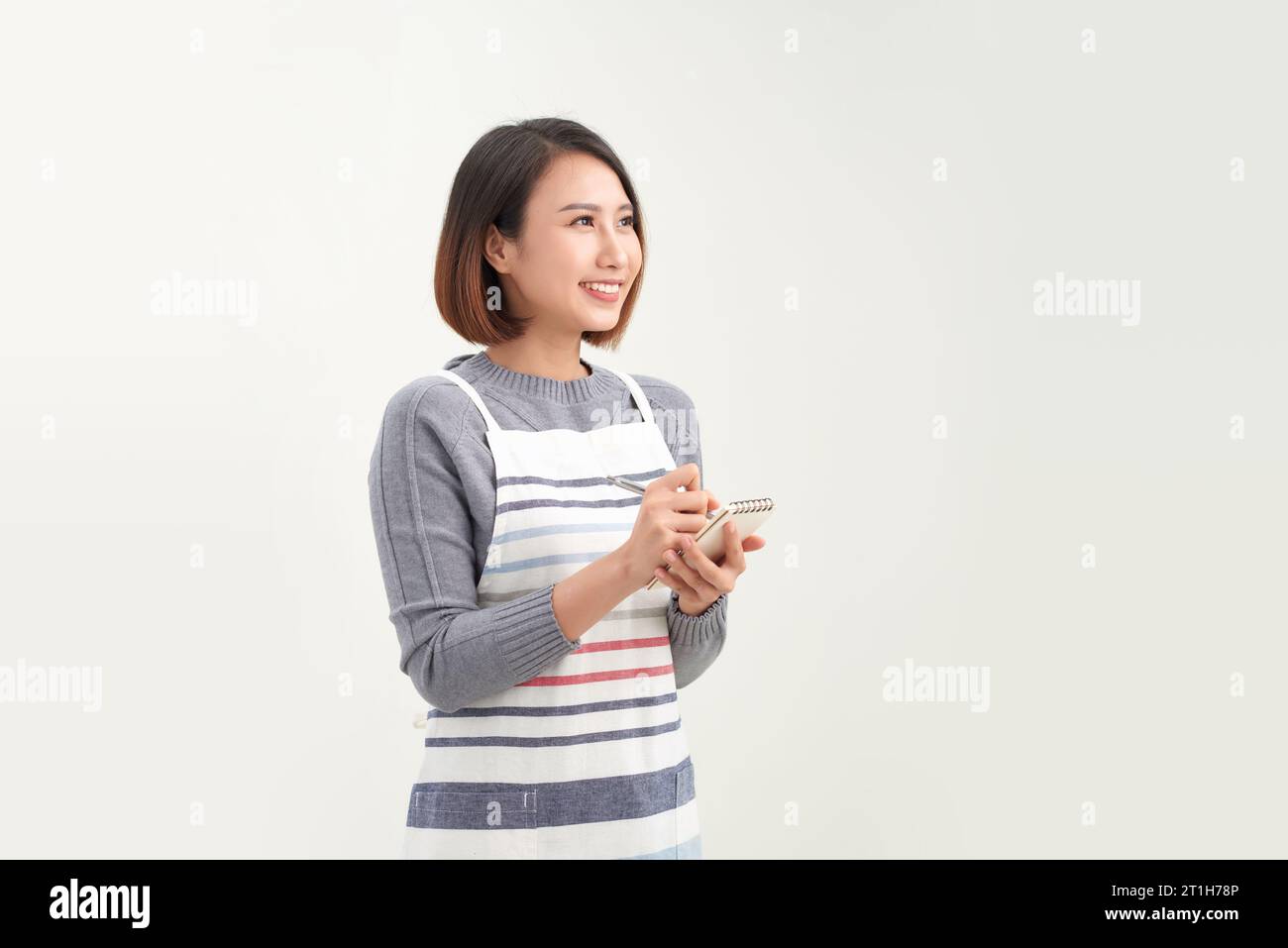 Jeune belle serveuse asiatique souriante confiante prenant des notes sur fond blanc Banque D'Images