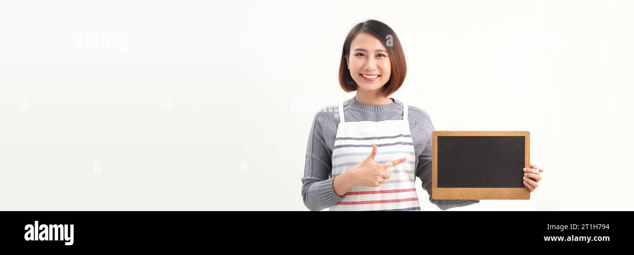 Serveuse se tenant au tableau vide et regardant la caméra tout en se tenant debout sur fond de bannière blanche. Banque D'Images