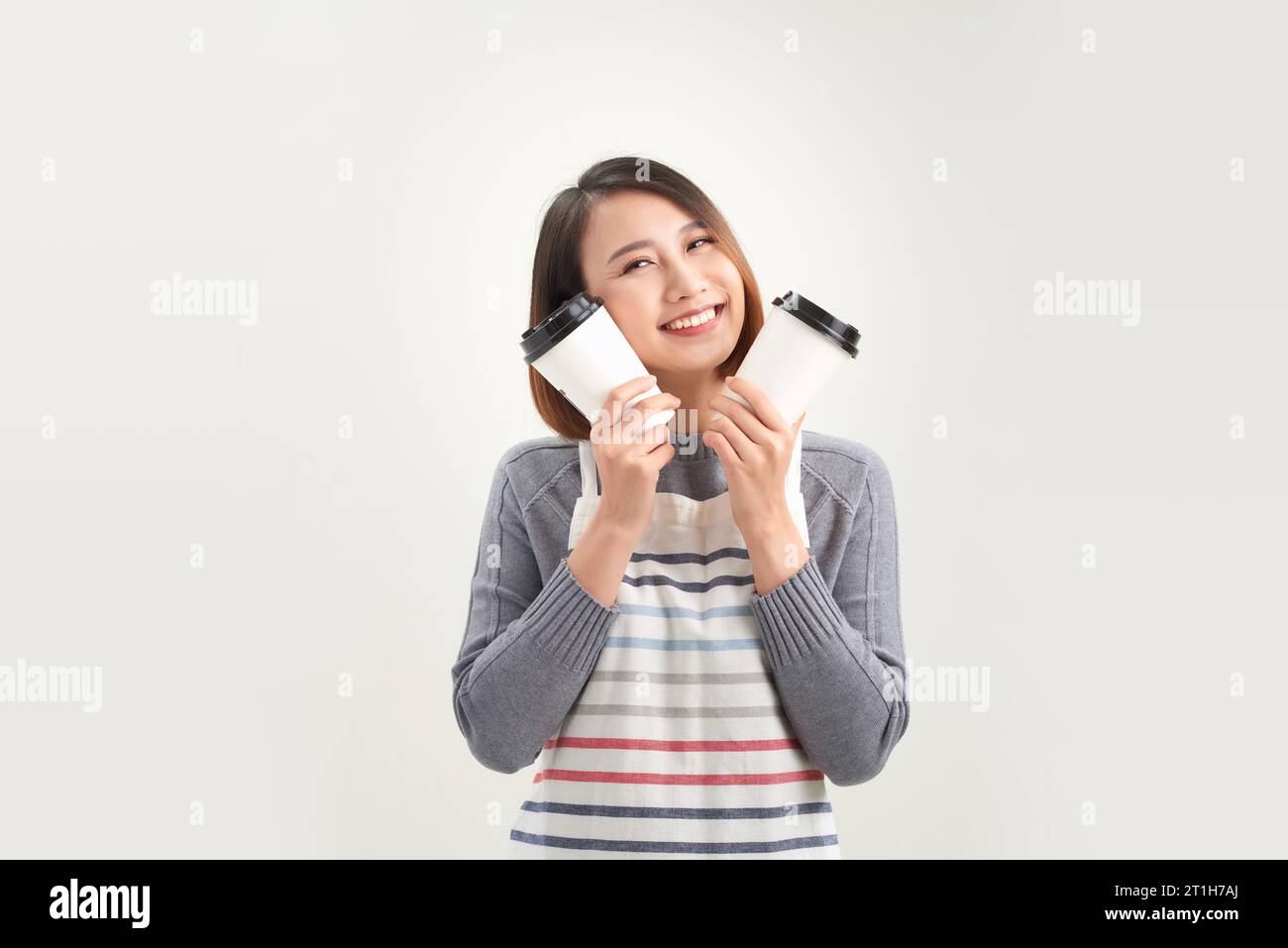 jeune femme en tablier tient deux gobelets de papier à emporter isolés sur fond blanc Banque D'Images