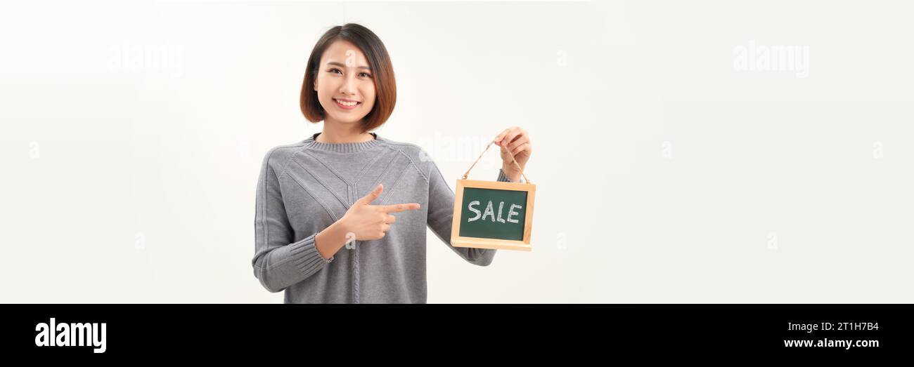 Belle femme asiatique en tablier de barista tenant le signe DE tableau noir de mot de VENTE sur fond blanc Banque D'Images