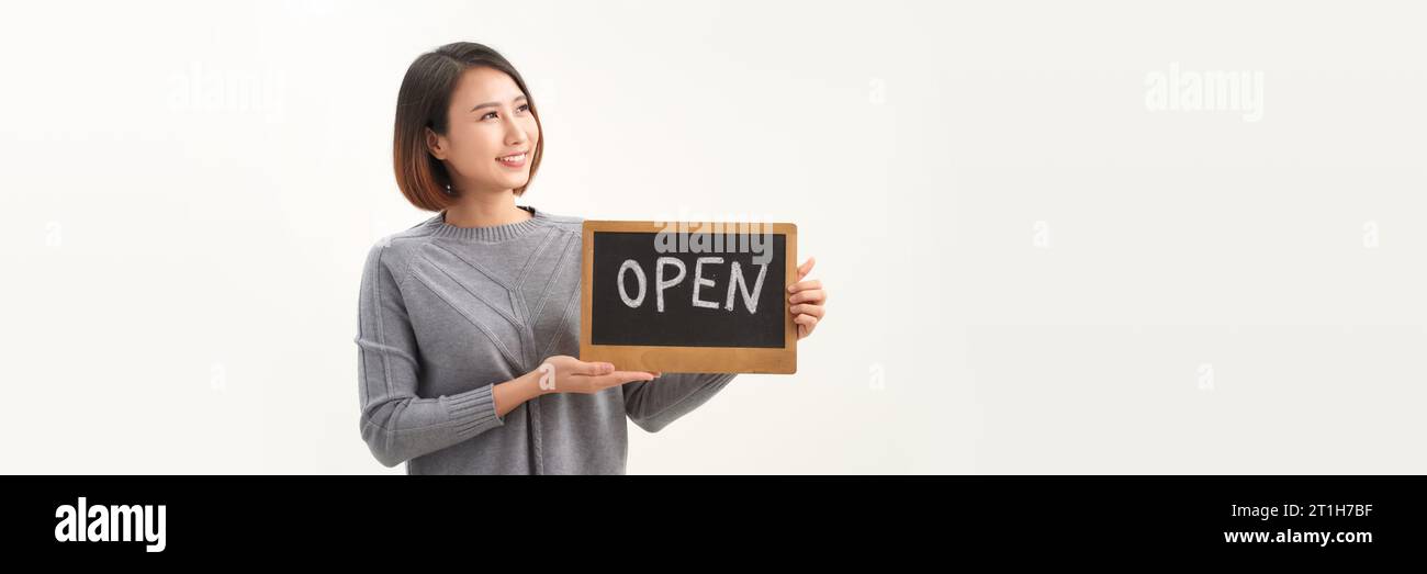 Jeune belle femme asiatique portant un tablier tenant un tableau noir ouvert sur fond blanc isolé Banque D'Images