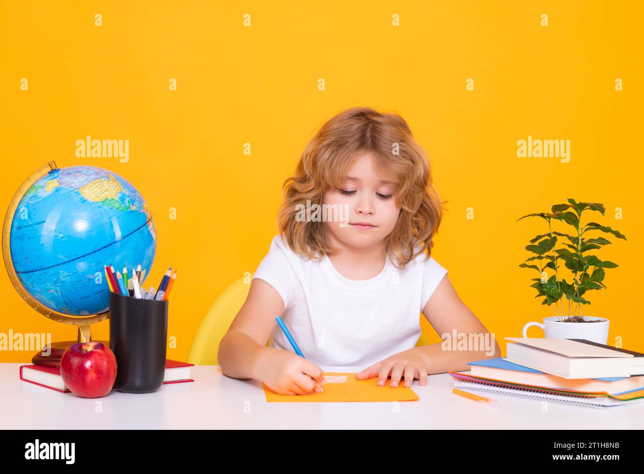 Retour à l'école. Drôle petit garçon de l'école primaire avec le livre. Portrait de garçon d'école isolé sur fond jaune de studio. Éducation Banque D'Images