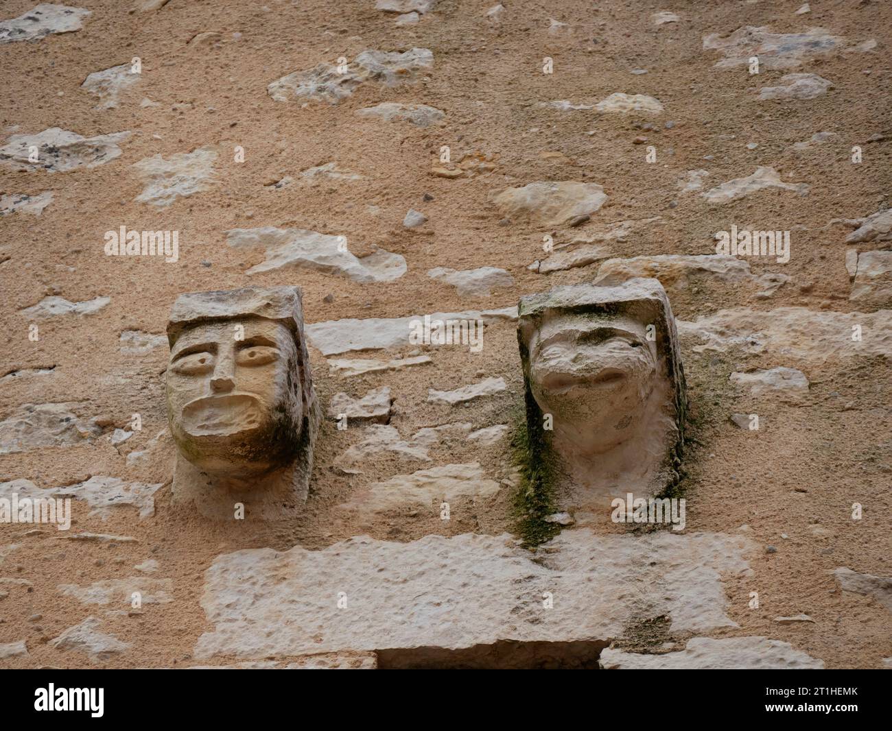 Modillions, sculptures de visages humains sur la façade de l'église à Payroux. L'art médiéval en France Banque D'Images