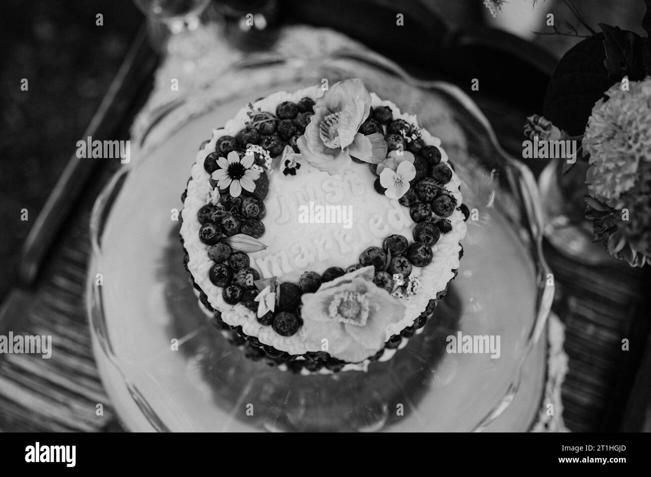 Un gâteau de mariage blanc fraîchement cuit, décoré avec une gamme vibrante de fruits et de fleurs Banque D'Images