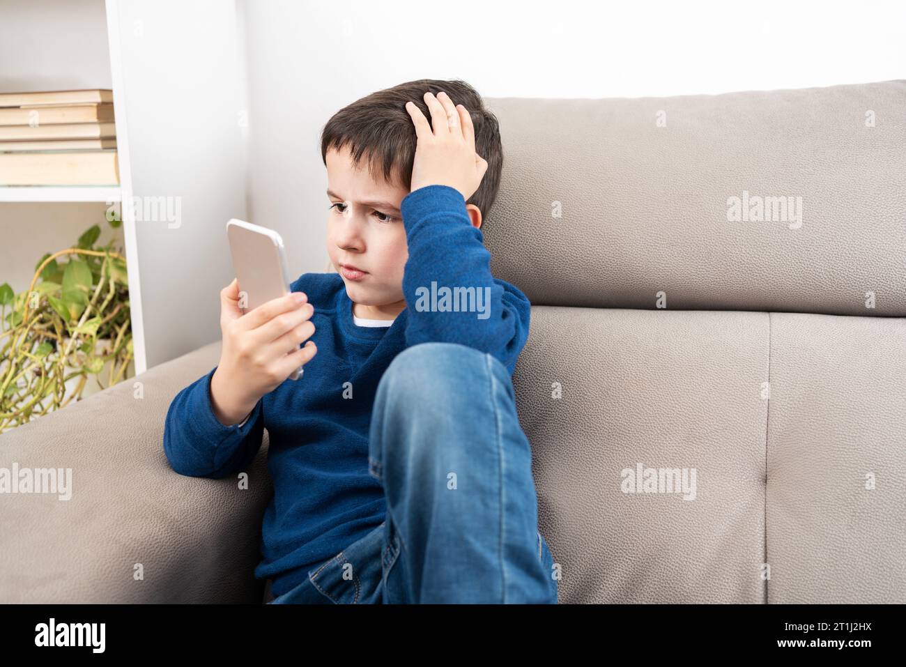 Portrait d'un garçon inquiet vérifiant le téléphone à la maison Banque D'Images
