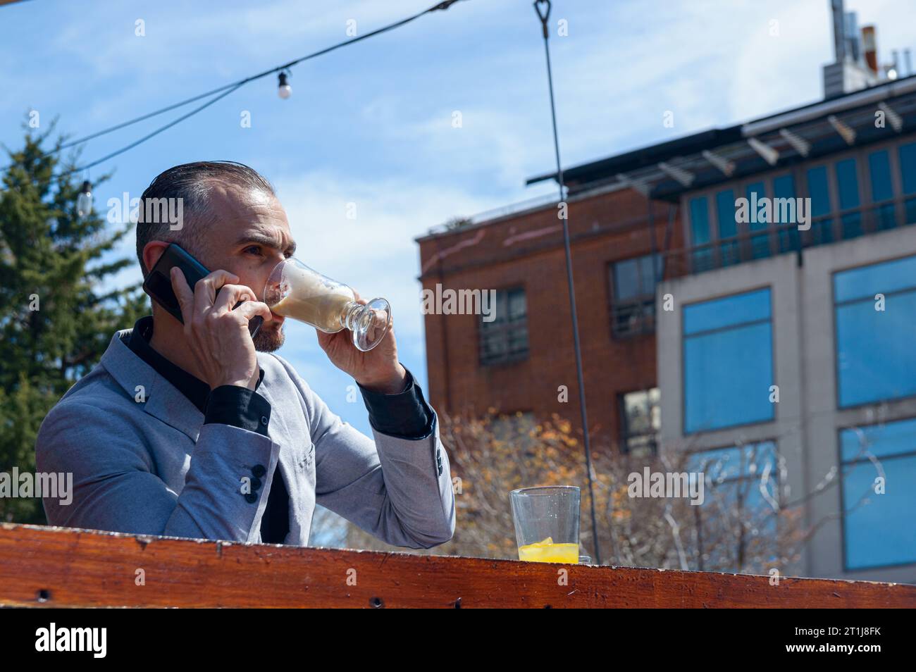 vue panoramique avec fond de ciel d'un homme adulte caucasien français dans des vêtements de travail exécutifs prenant le petit déjeuner assis boire un café au bar du restaurant Banque D'Images