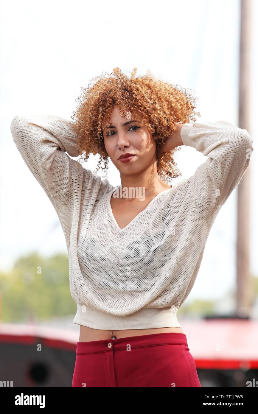 Portraits en plein air d'une femme blonde aux cheveux bouclés avec un pull blanc et un pantalon rouge Banque D'Images